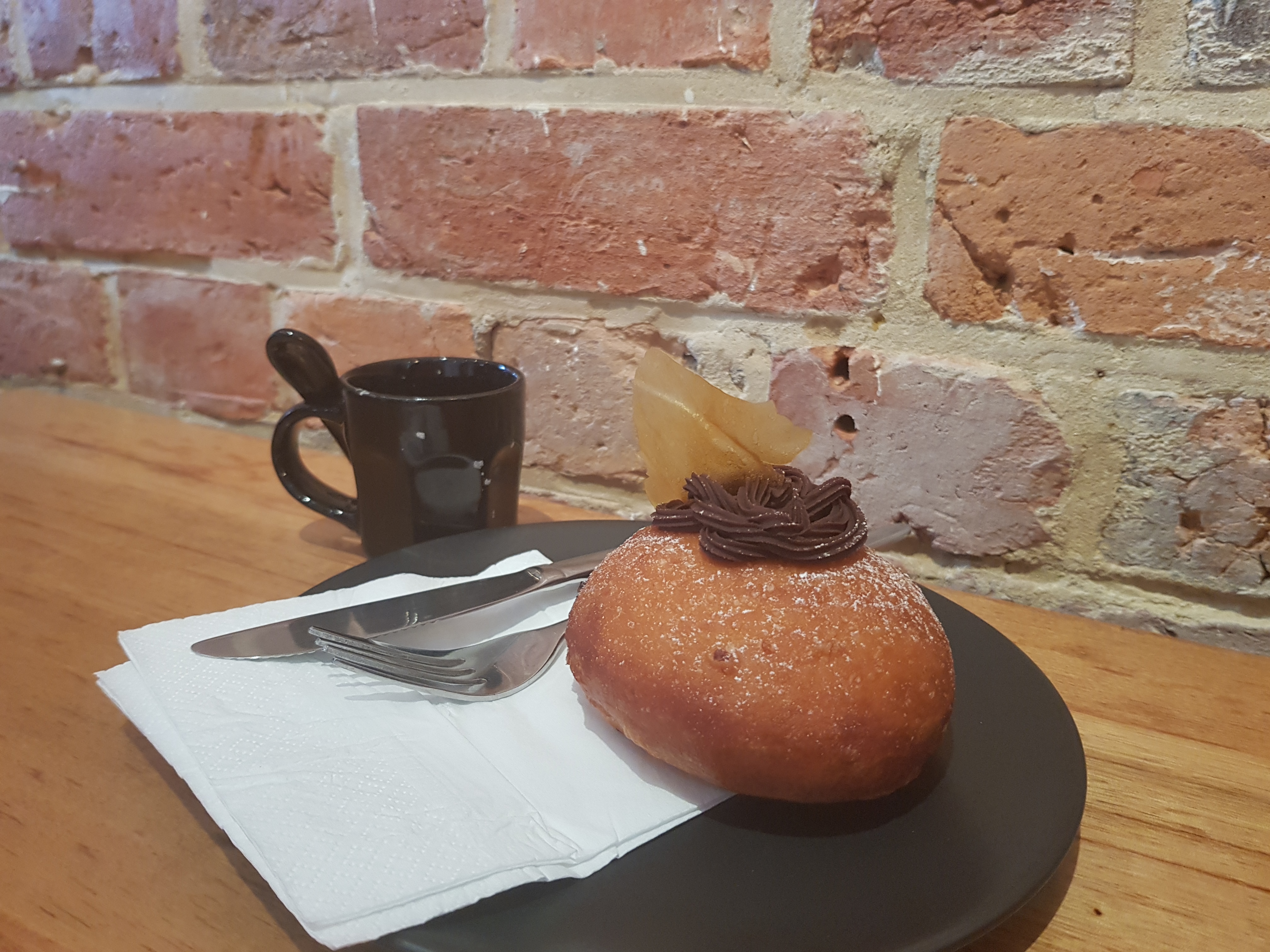 A nicely decorated donut on a black plate.