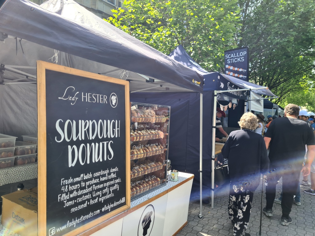 a large sign reads "Lady Hester: Sourdough Donuts" a small display cabinet sits beside the sign with the flavours of the day written on it. 